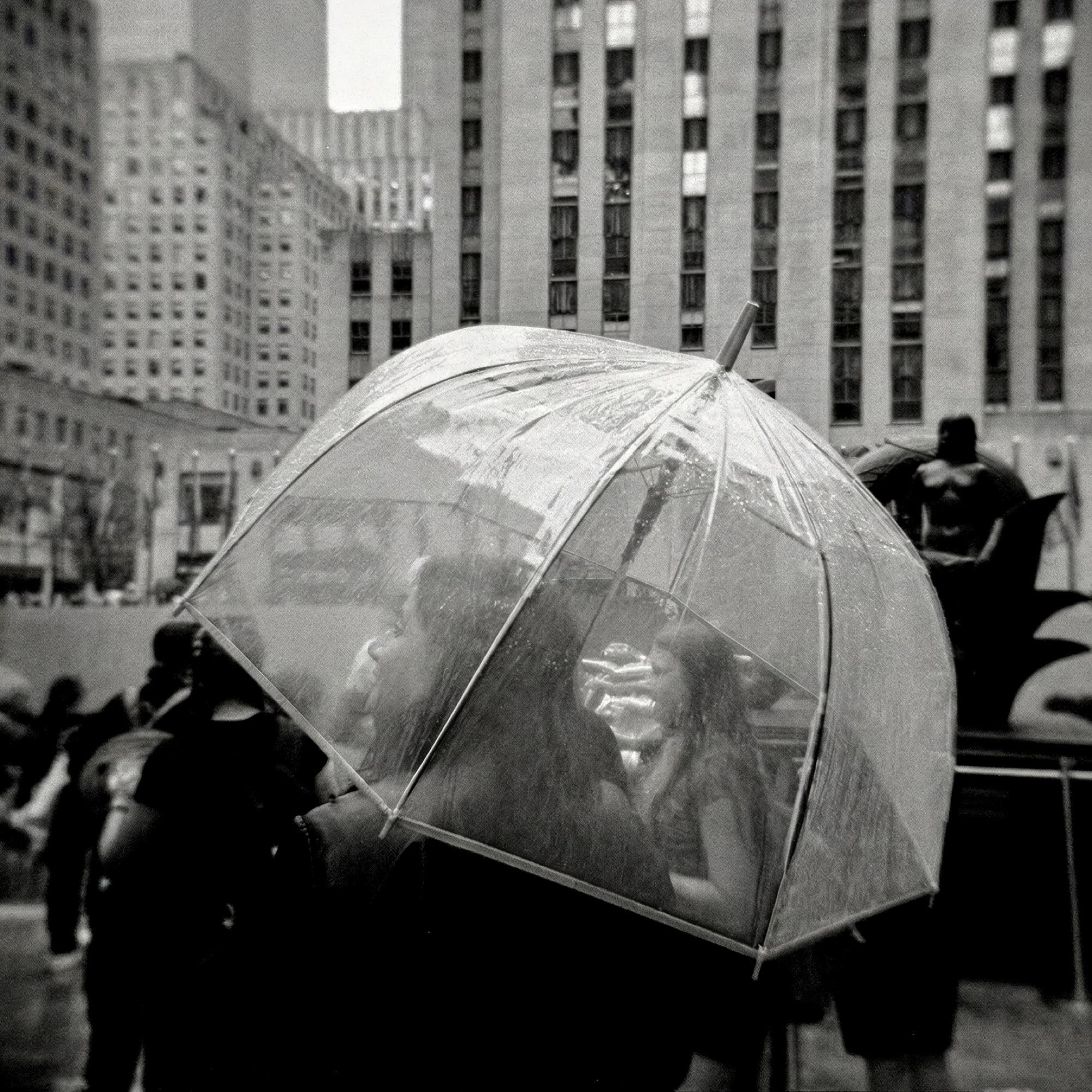 Rockefeller Center, NYC — couple beneath a clear umbrella, B&W, by G. John Slagle.